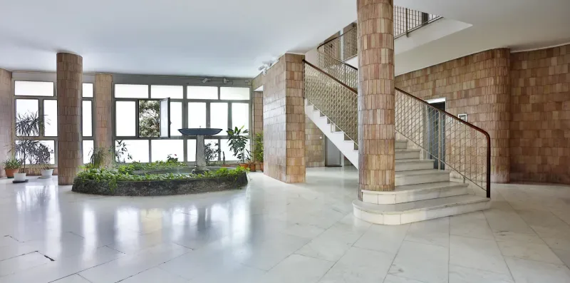 A bright interior lobby with a curved staircase and large windows.