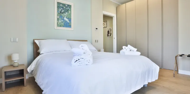 A bedroom with a neatly made bed and a framed picture on the wall.