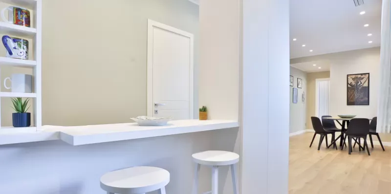A bright dining area with a dark table and chairs beside a white counter.