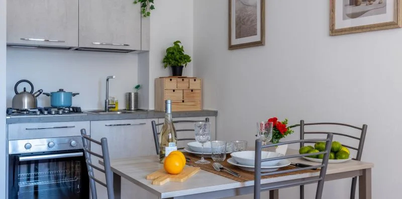 A compact kitchen and dining area with a set table and potted plants.