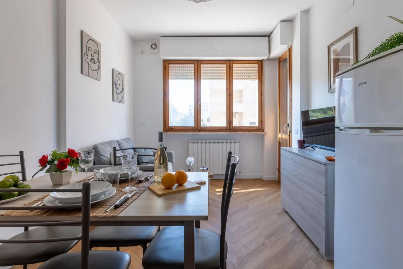A dining area with a set table beside a bright window.