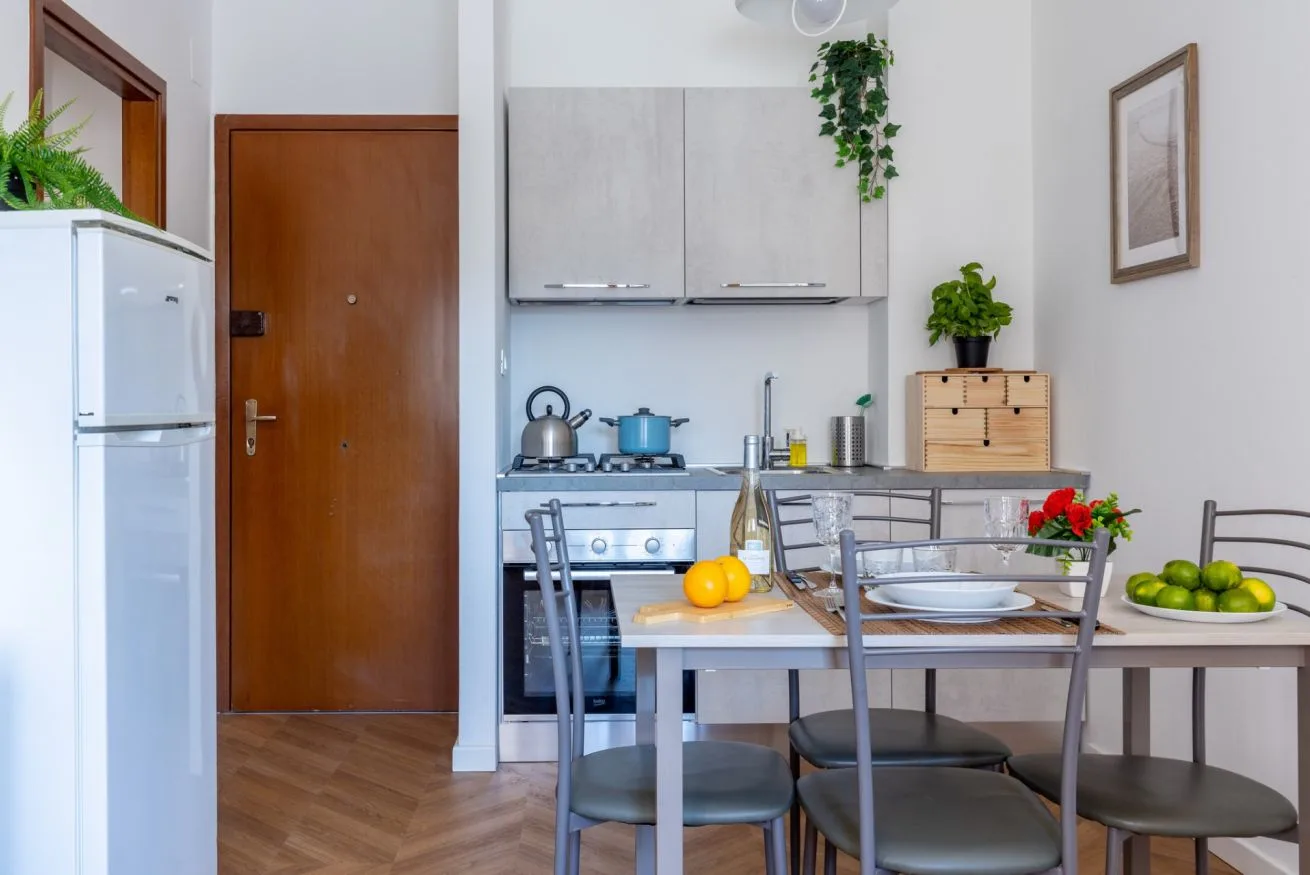A kitchen and dining area with a table set with dishes and fruit.