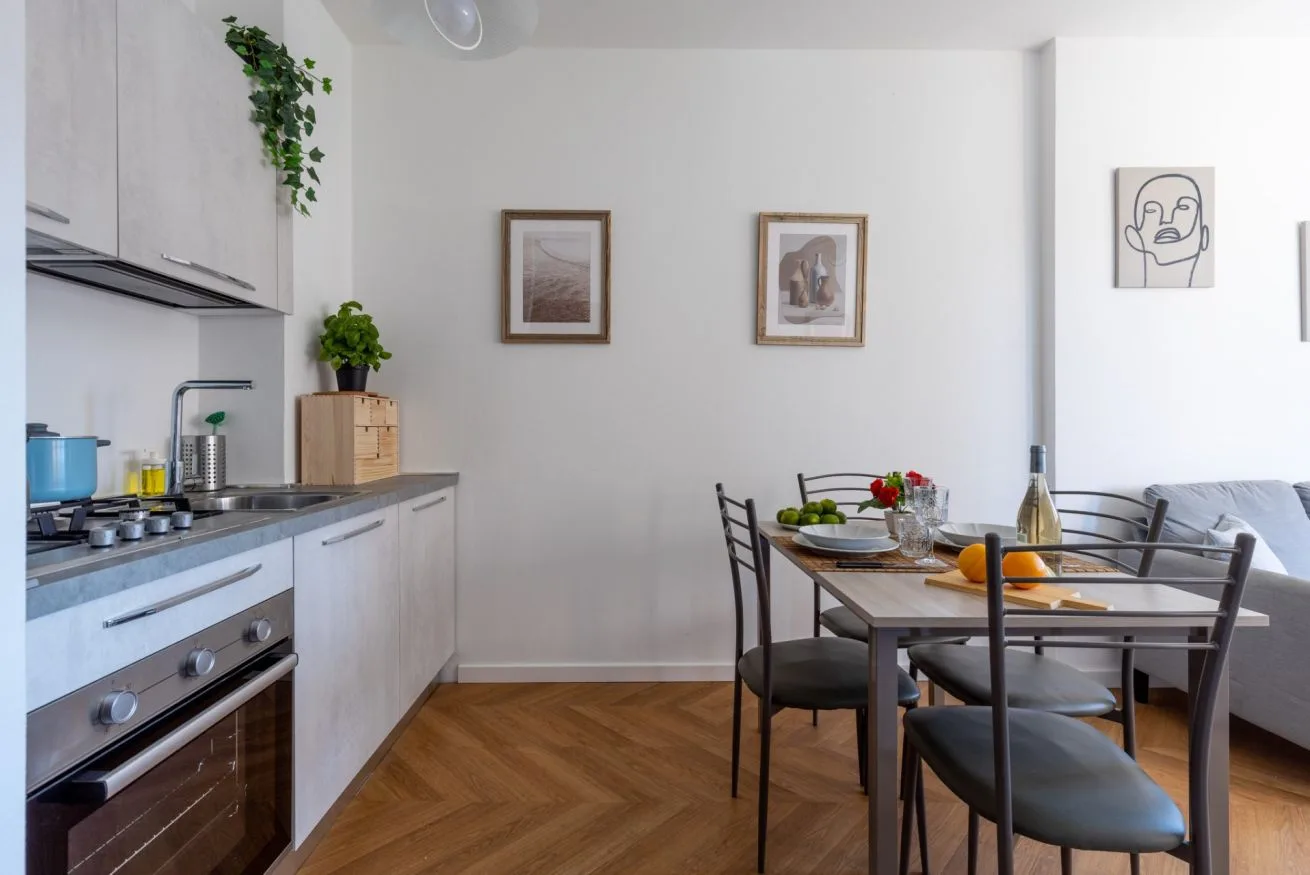 A bright kitchen and dining area with a set table and framed wall art.