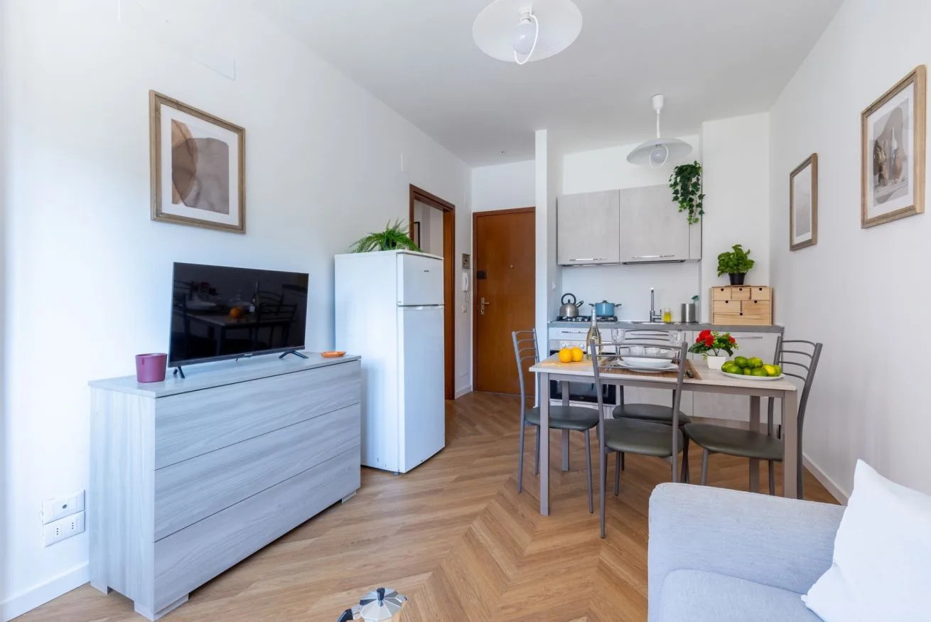 A bright living and dining area with a television, dining table, and seating.
