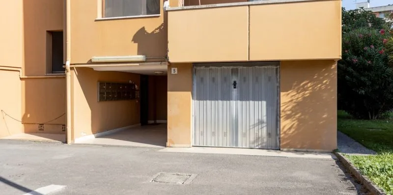 Exterior view of an apartment building with a garage entrance and paved driveway.