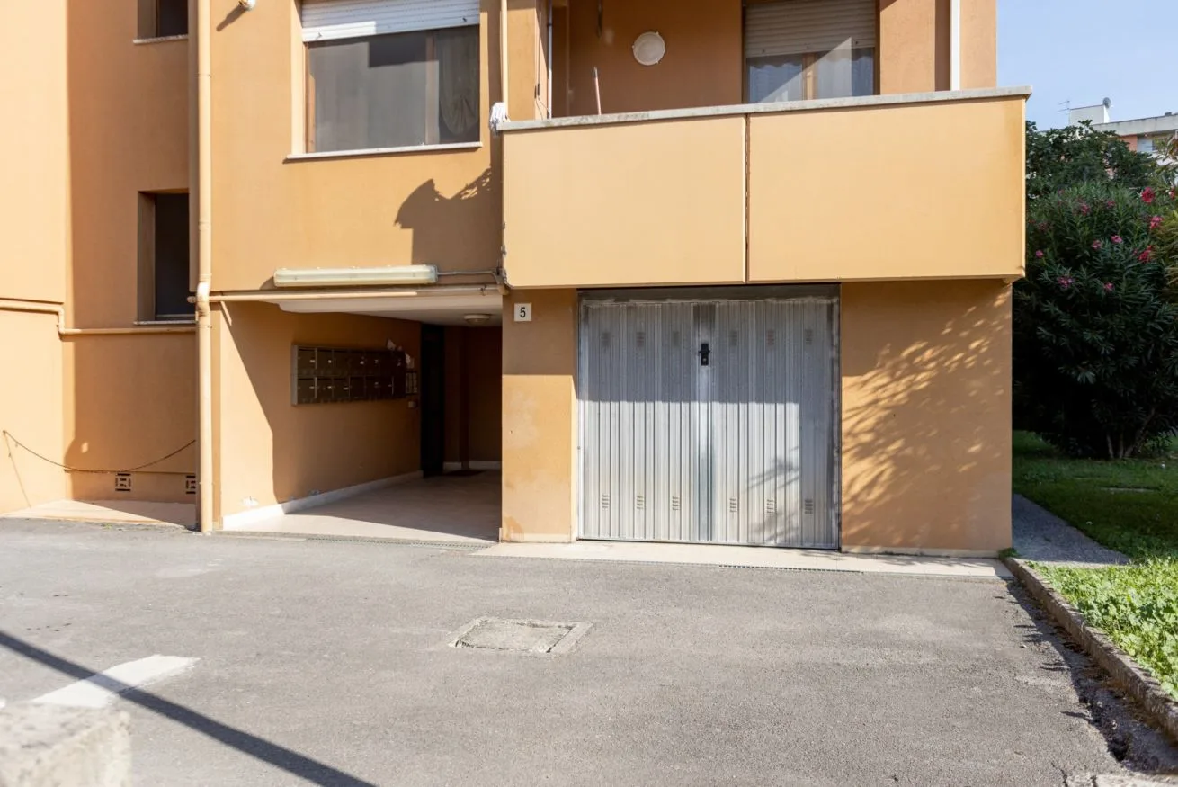 A peach-colored apartment building entrance faces a paved driveway.