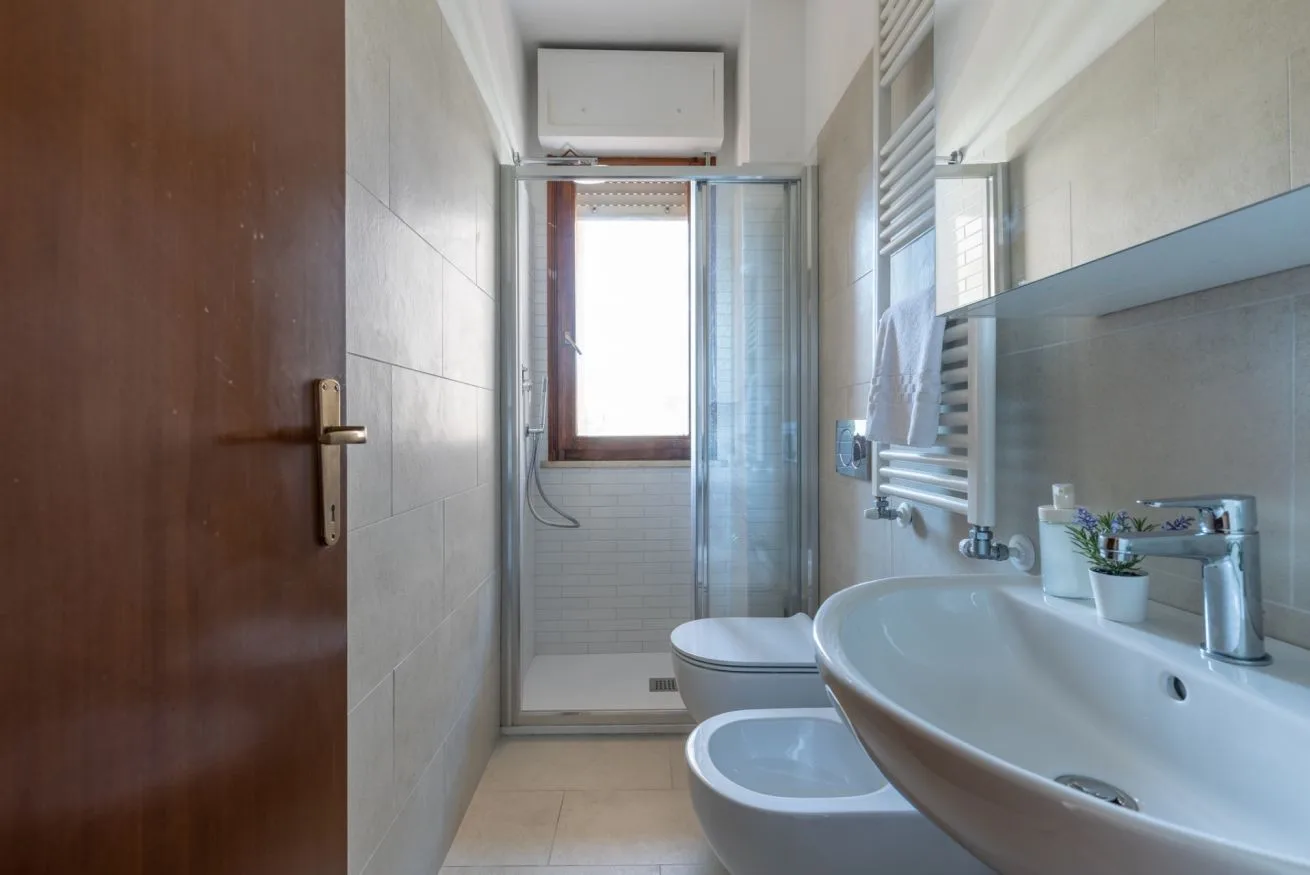 A tiled bathroom with a shower, toilet, and sink.