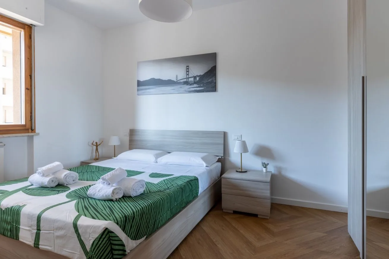 A bedroom with a double bed dressed in green and white bedding.