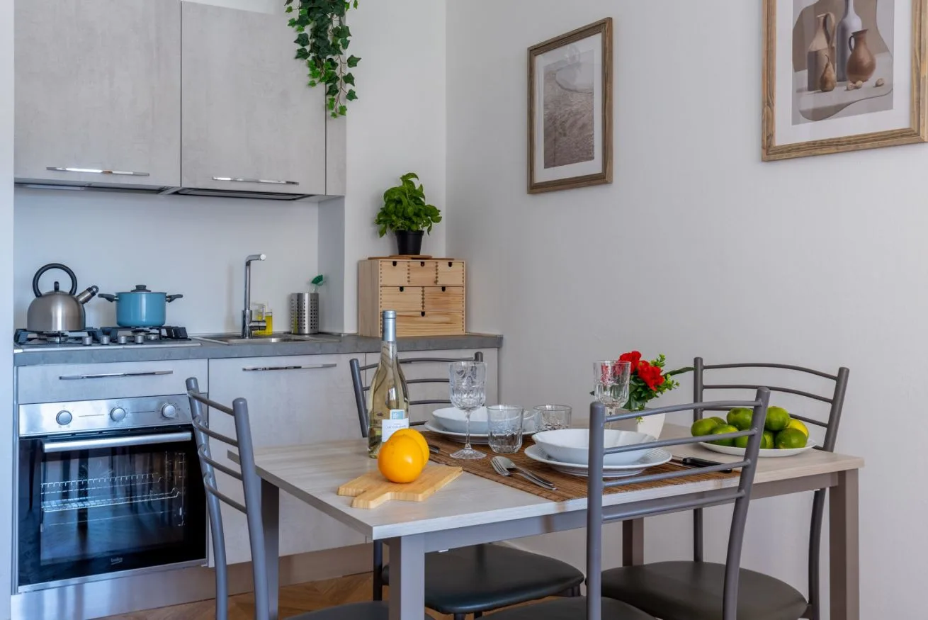 A compact kitchen and dining area with a set table and blue kettle.