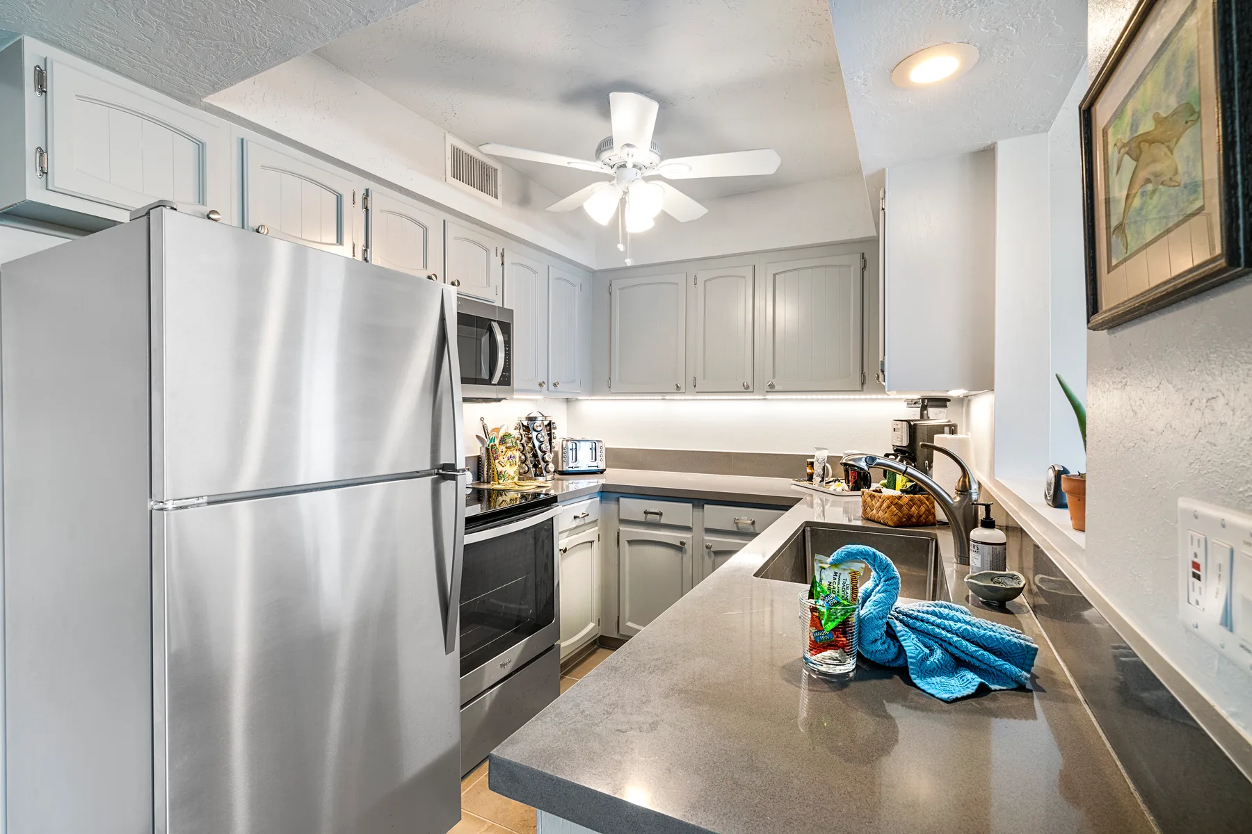 A bright kitchen with pale cabinets and a central countertop.
