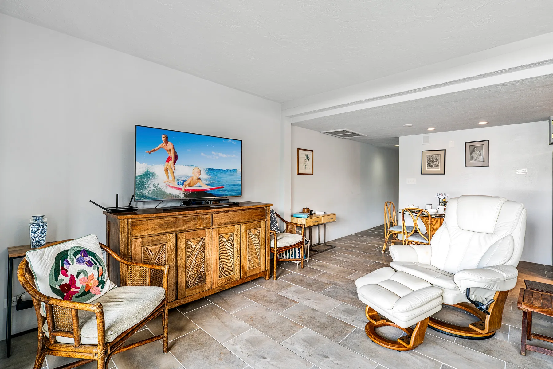 A living room with a television, wooden cabinet, and white seating.