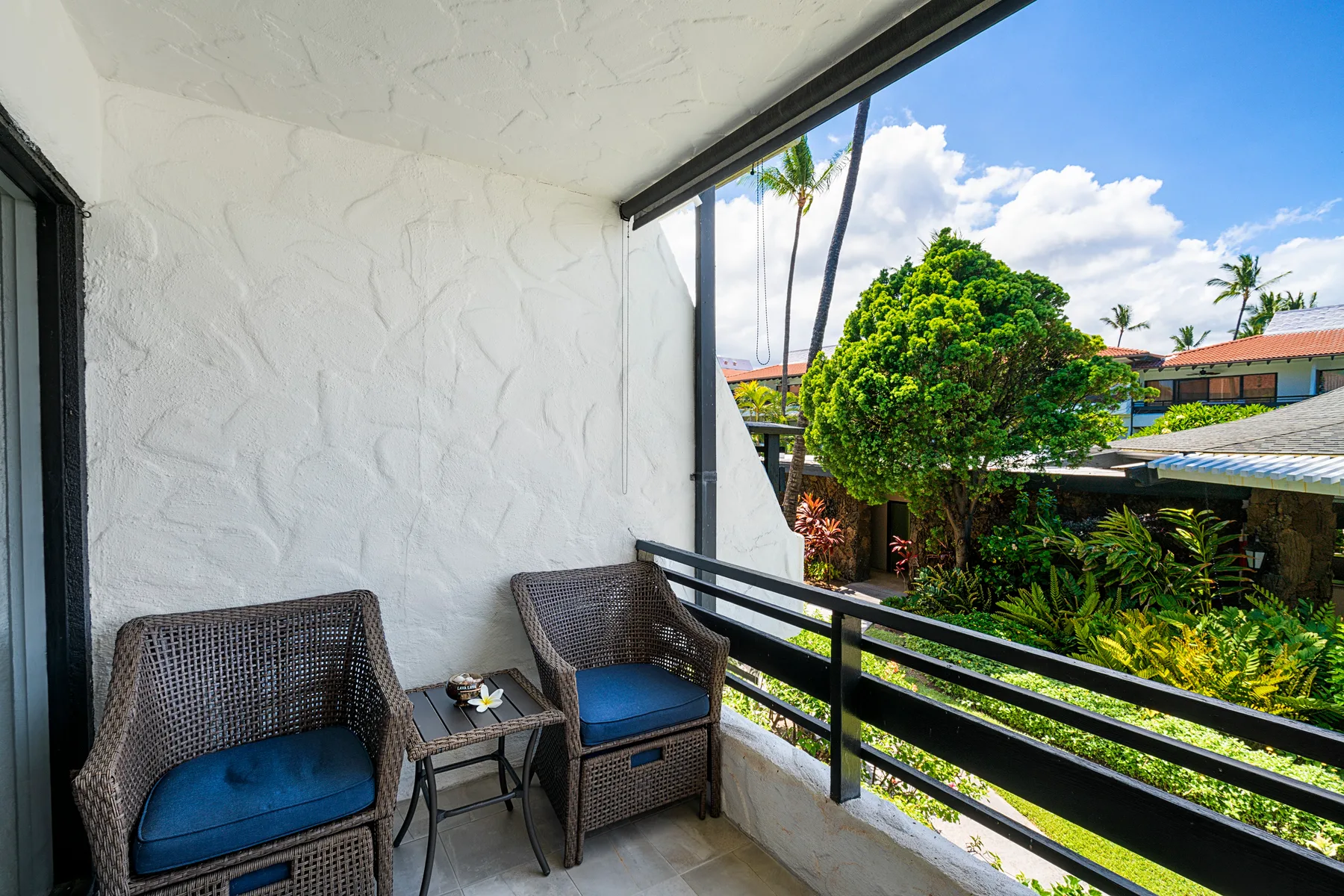 A balcony seating area overlooks green trees and nearby buildings.