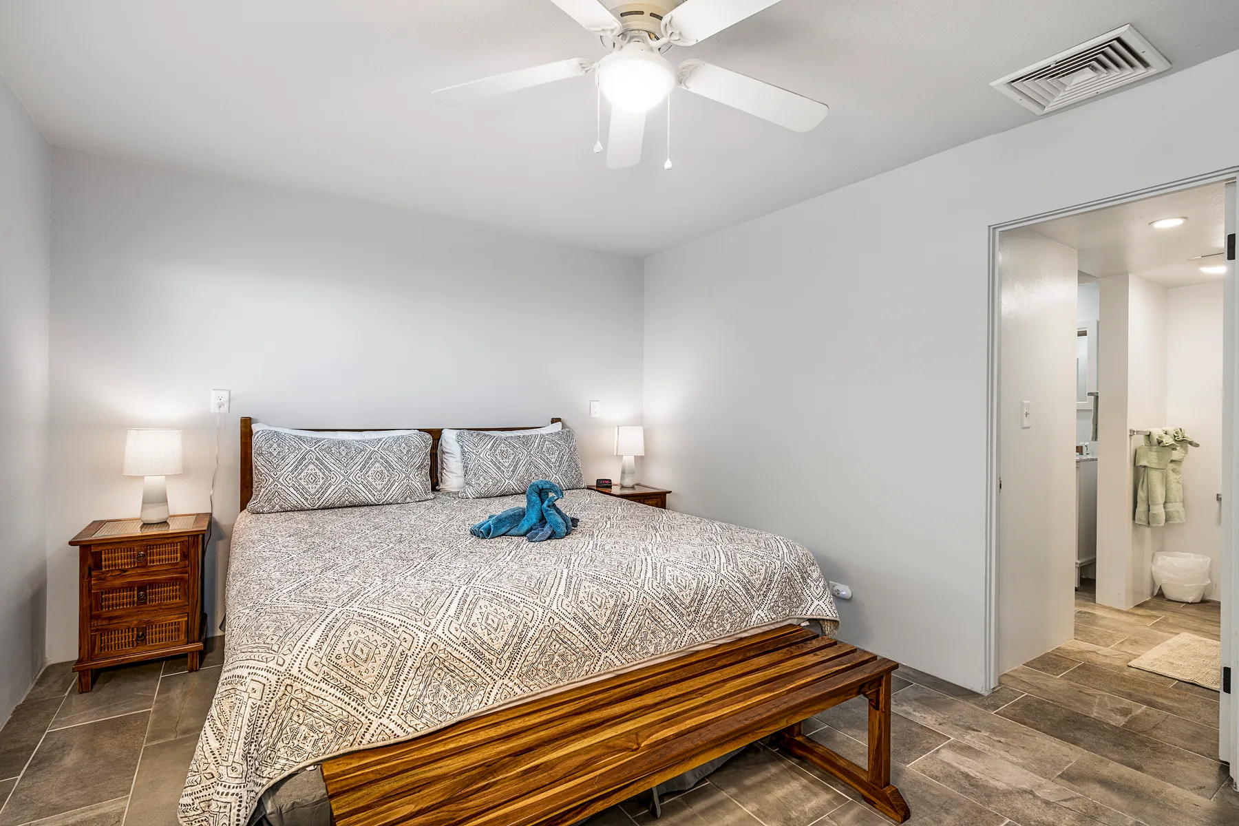 A bedroom with a large bed, bedside tables, and an open doorway to a bathroom.