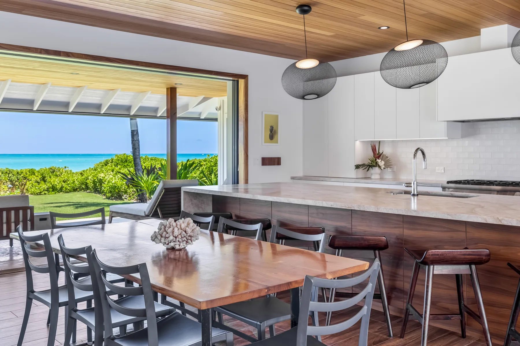 An open dining and kitchen area with a large table overlooking the ocean.