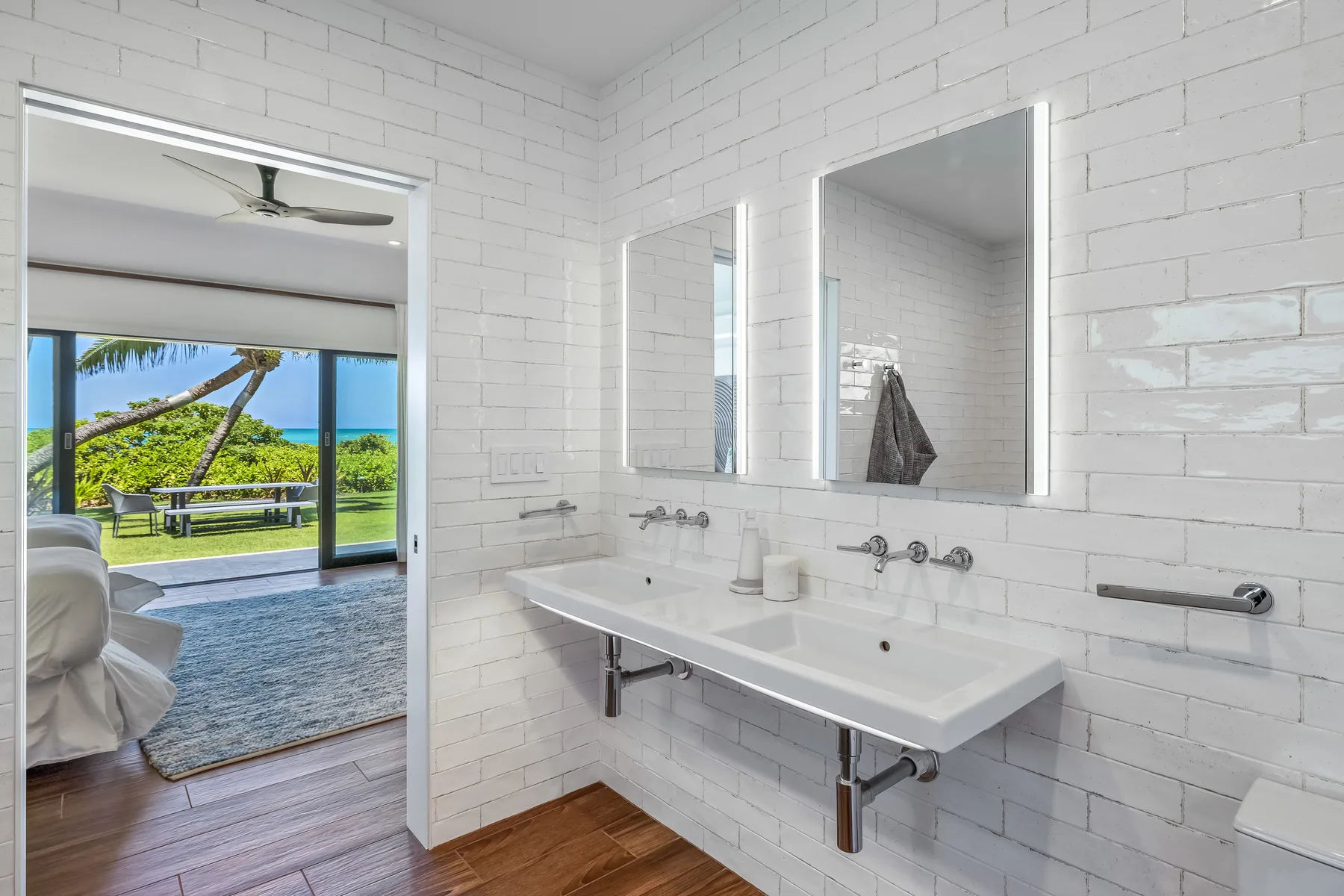 A bright bathroom with a long white sink and mirrors above it.
