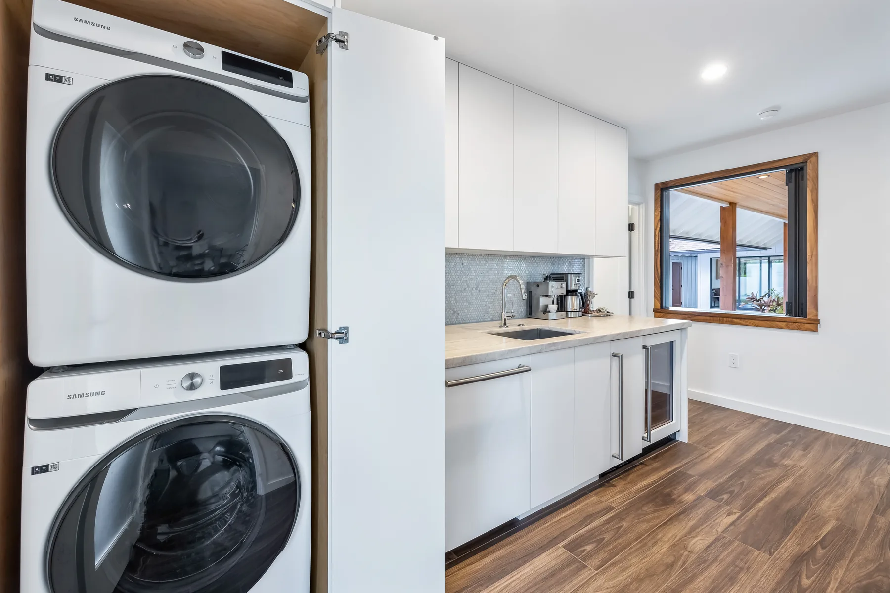 A laundry area with stacked appliances, white cabinets, and a counter.