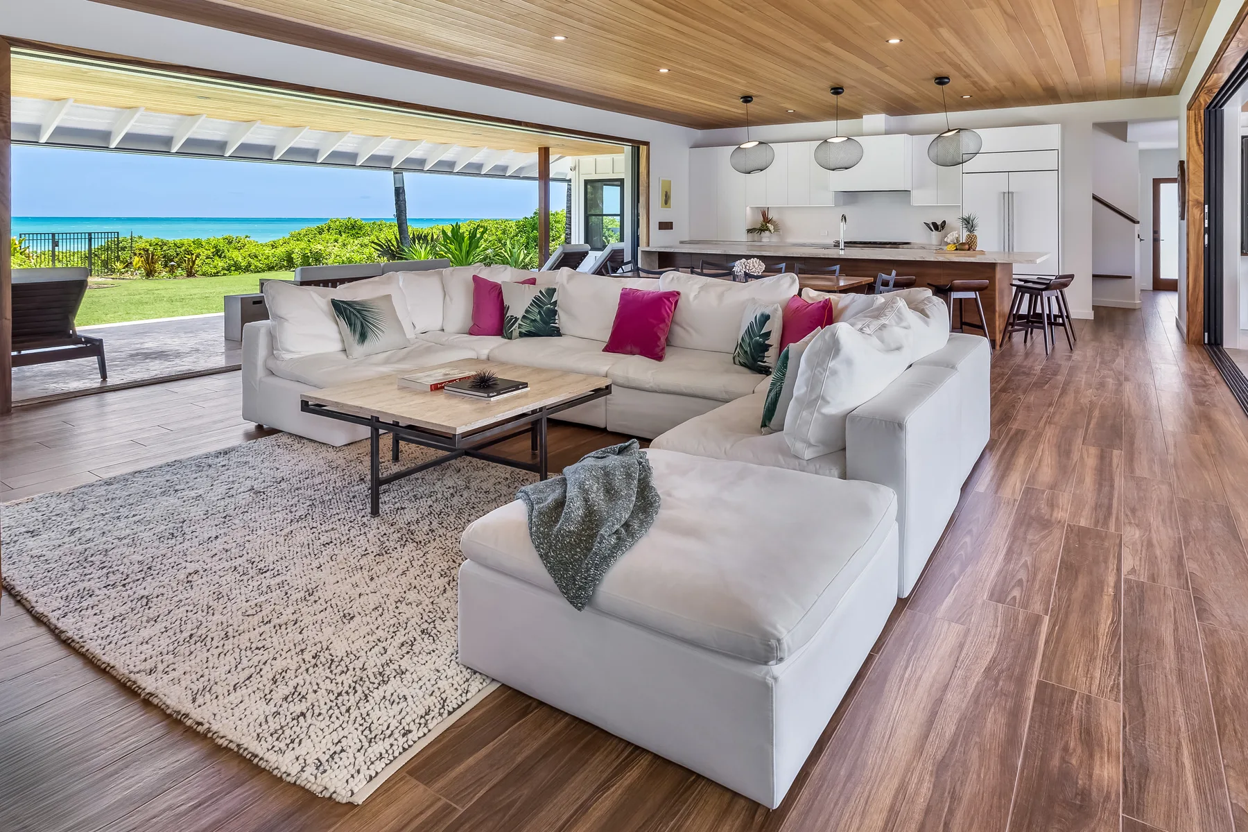 Una sala de estar abierta con asientos seccionales y una cocina con vista al mar.