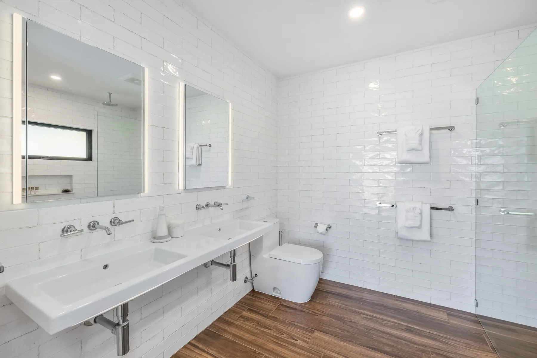 A bright bathroom with a long sink counter and a glass shower.