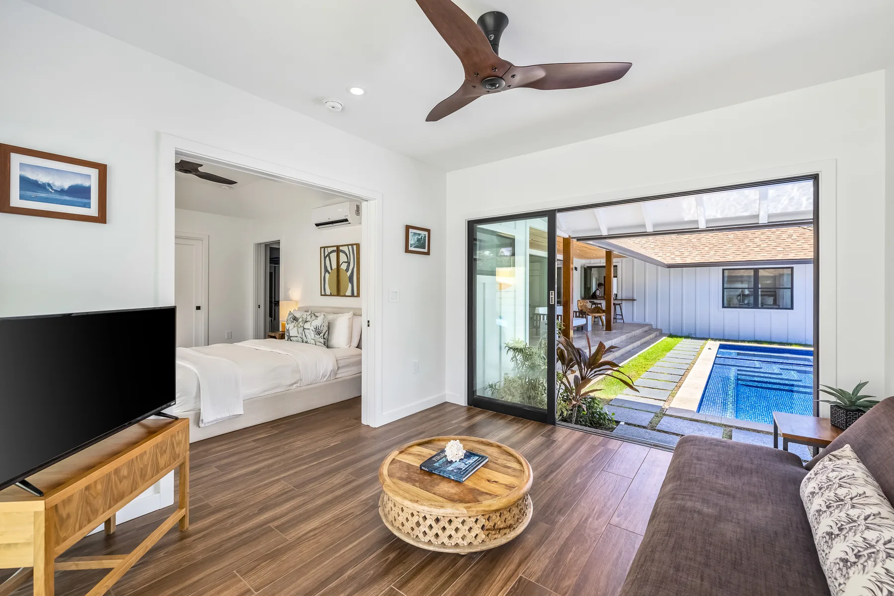 A bright living room opens through sliding glass doors to a pool courtyard.