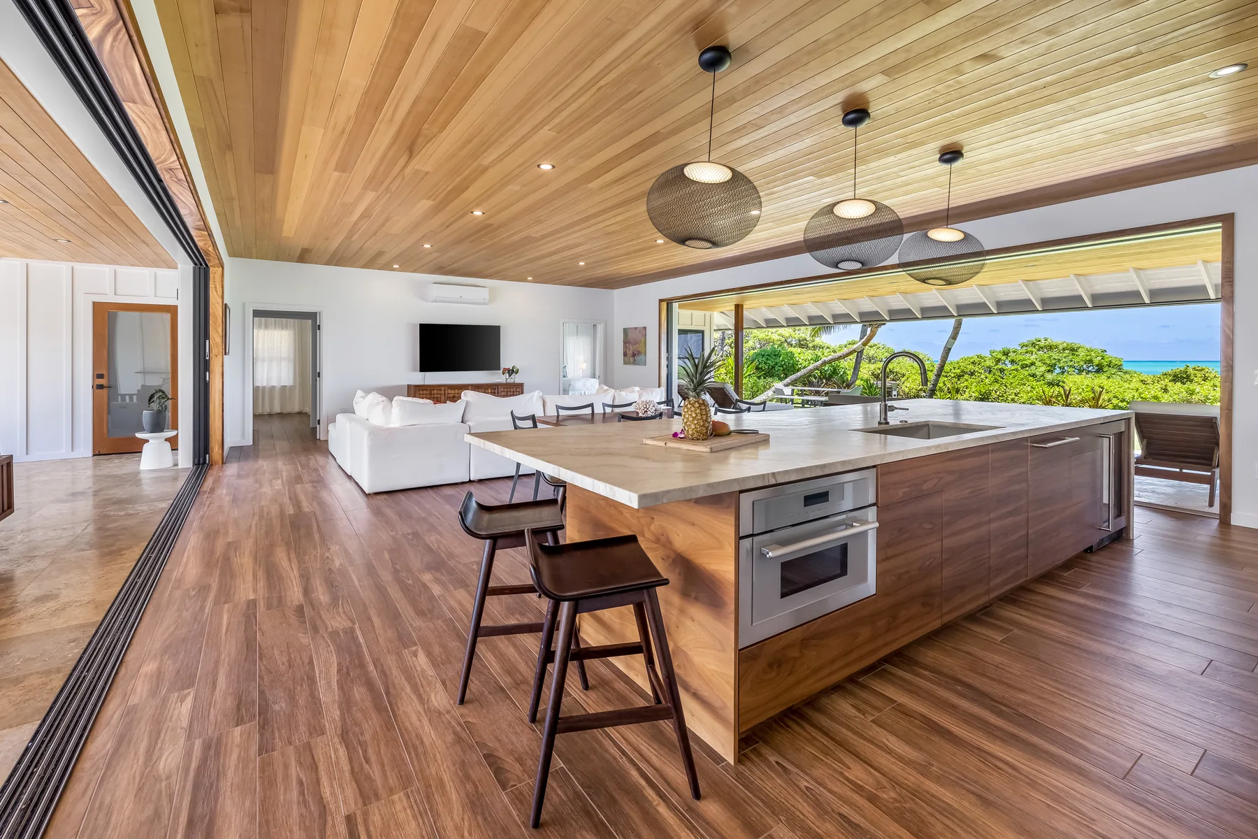 An open-plan kitchen and living area with a large island and white seating.