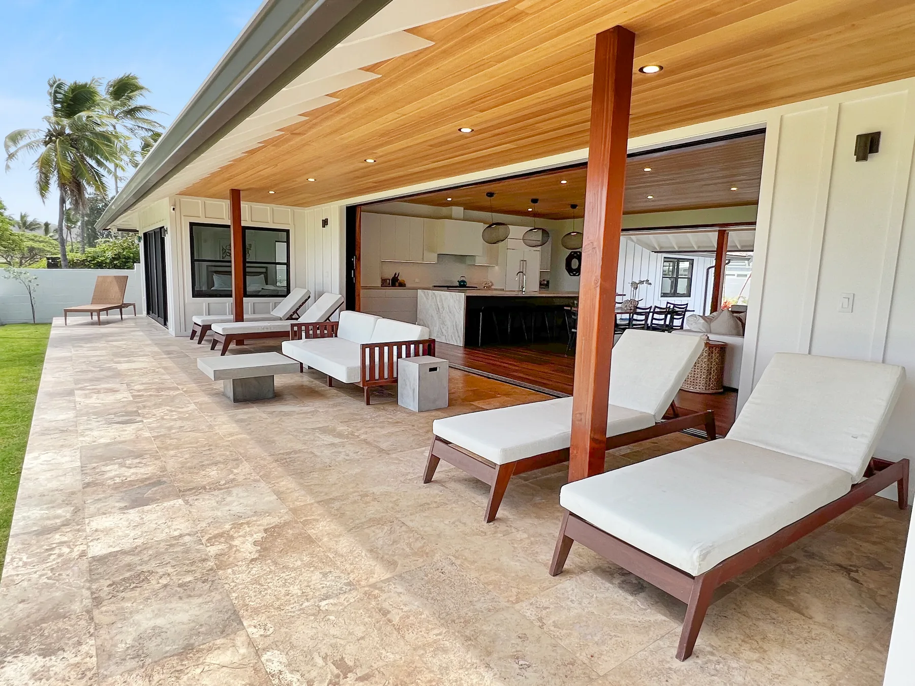 Una amplia terraza exterior con asientos acolchados junto a un interior diáfano.