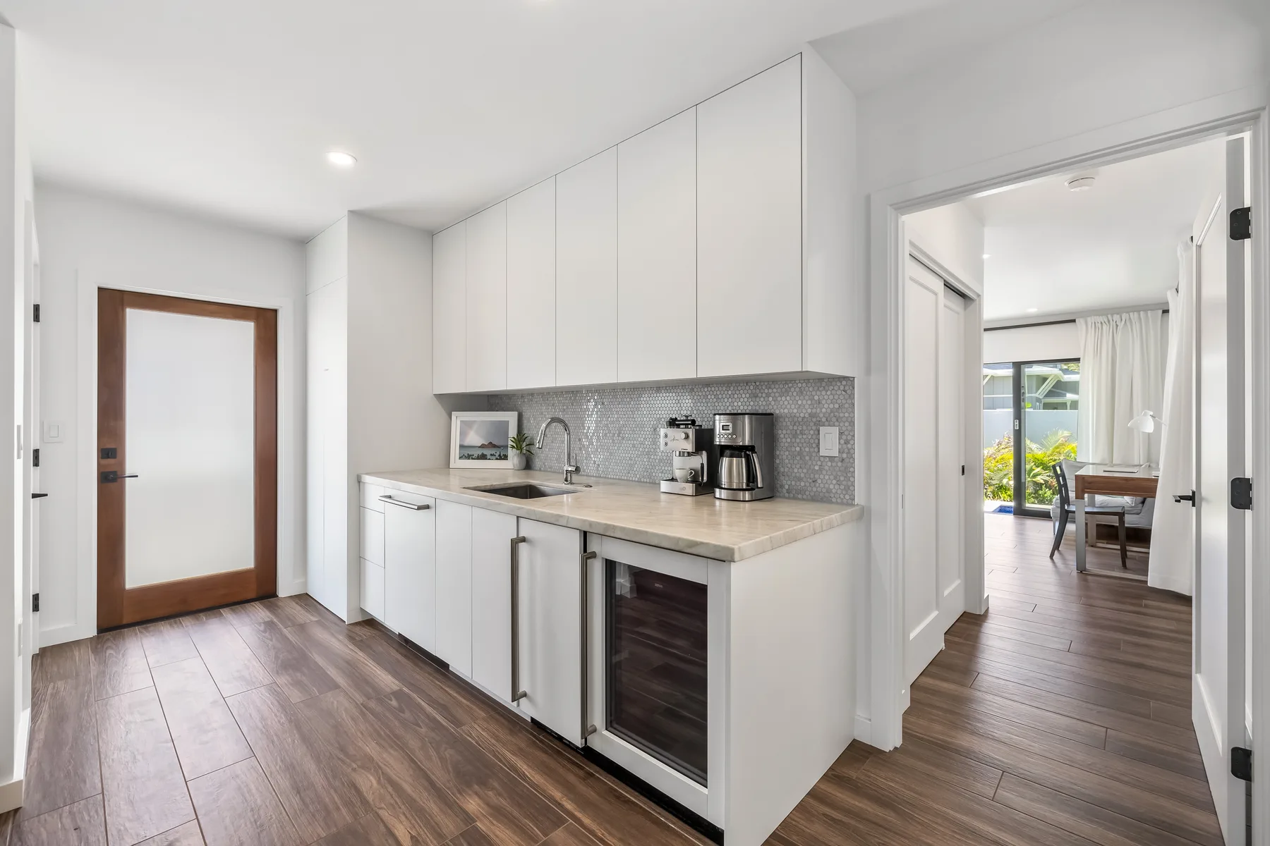 A bright kitchen with white cabinets, a countertop, and a tiled backsplash.