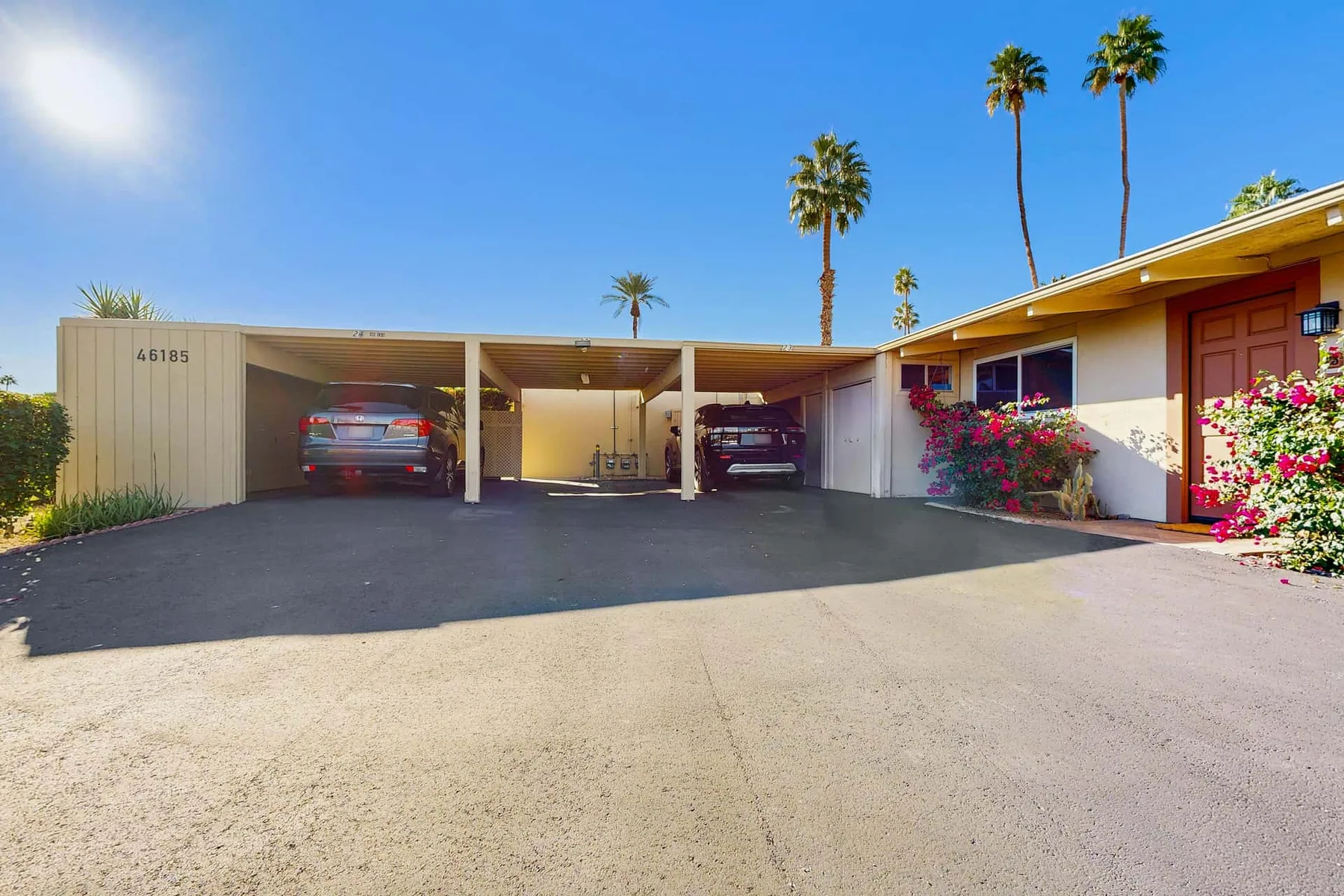 A paved parking area with covered carports beside a low building.