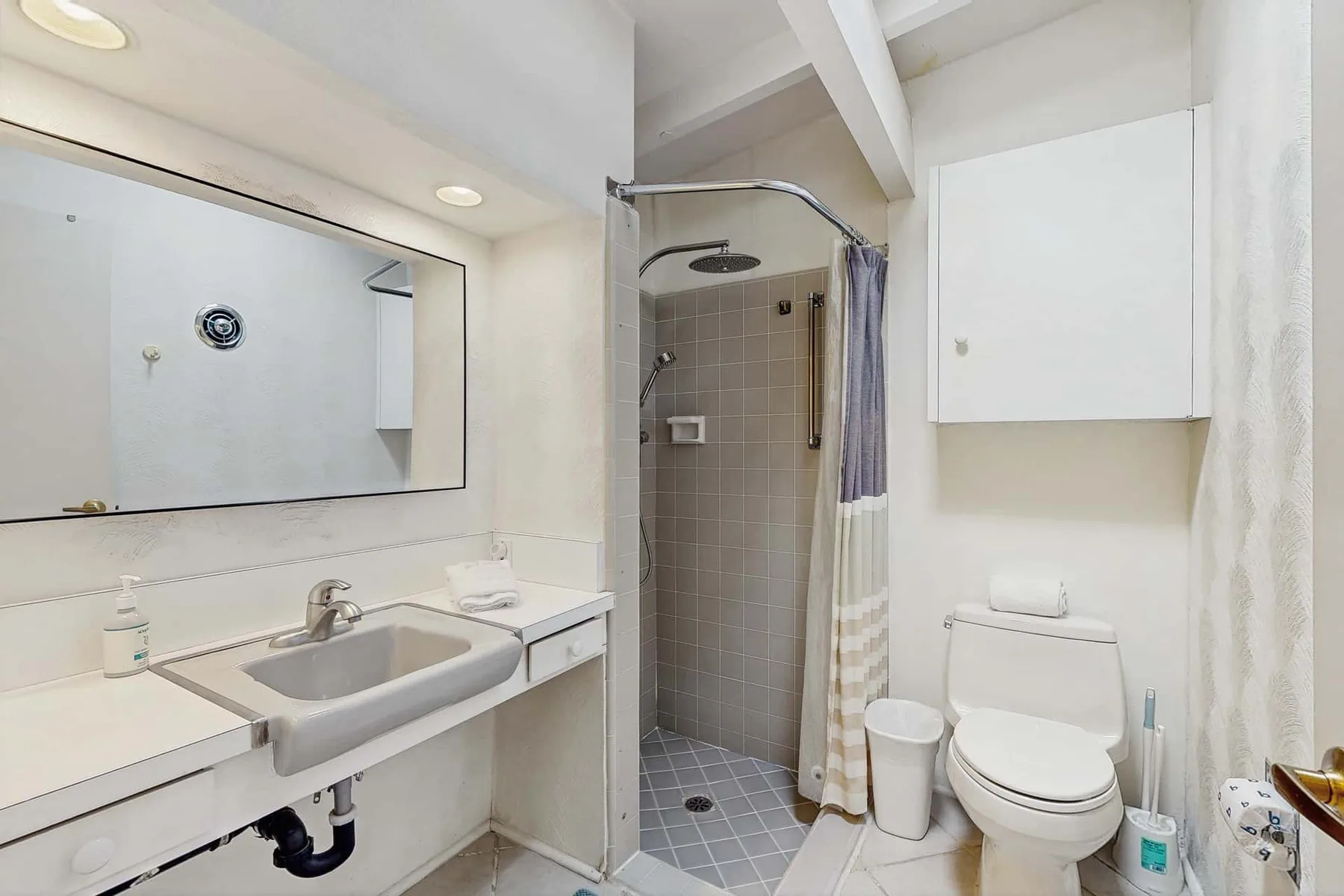 A bathroom with a sink, toilet, and tiled shower.