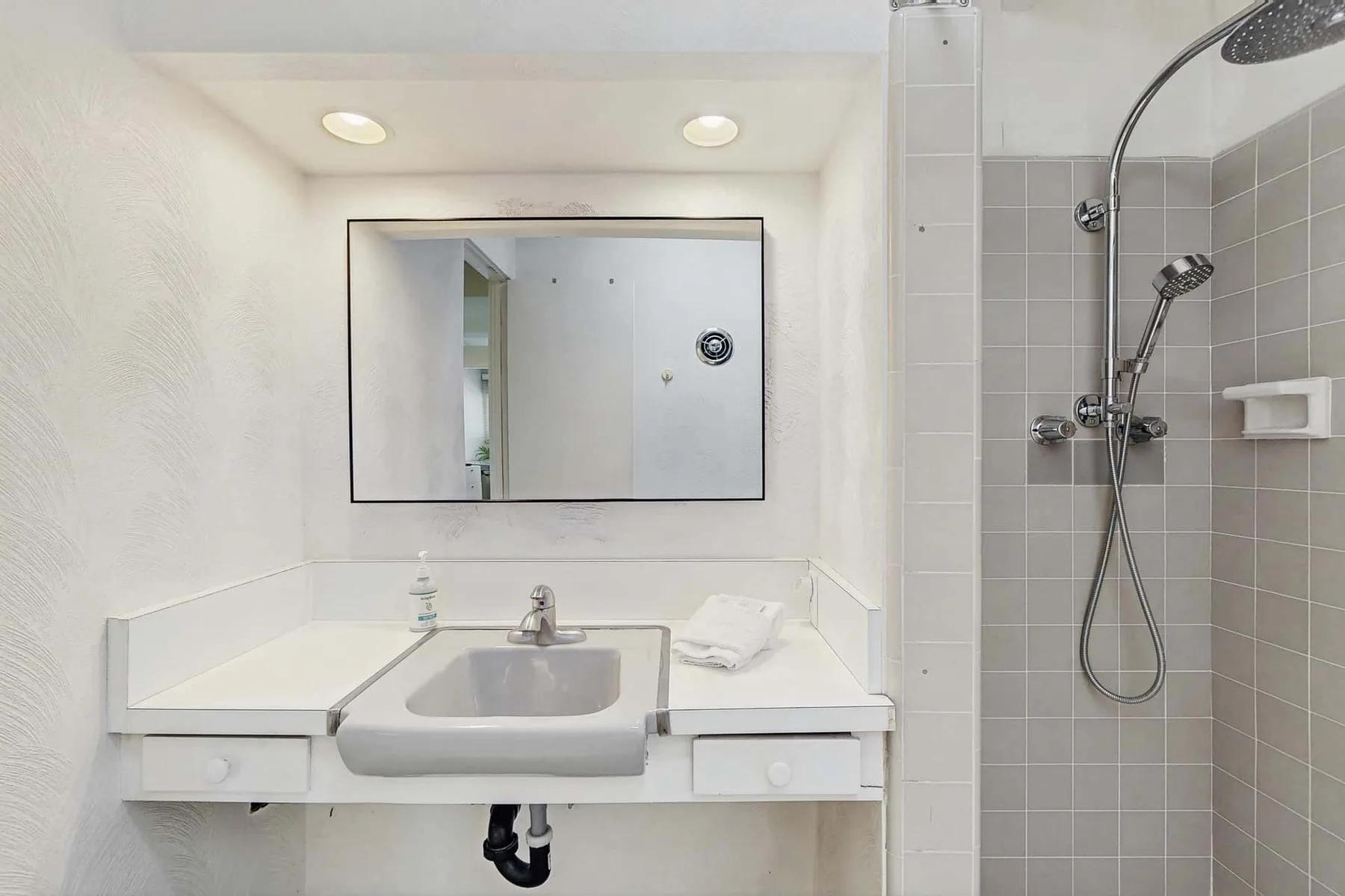A bathroom vanity with a sink and a tiled shower.