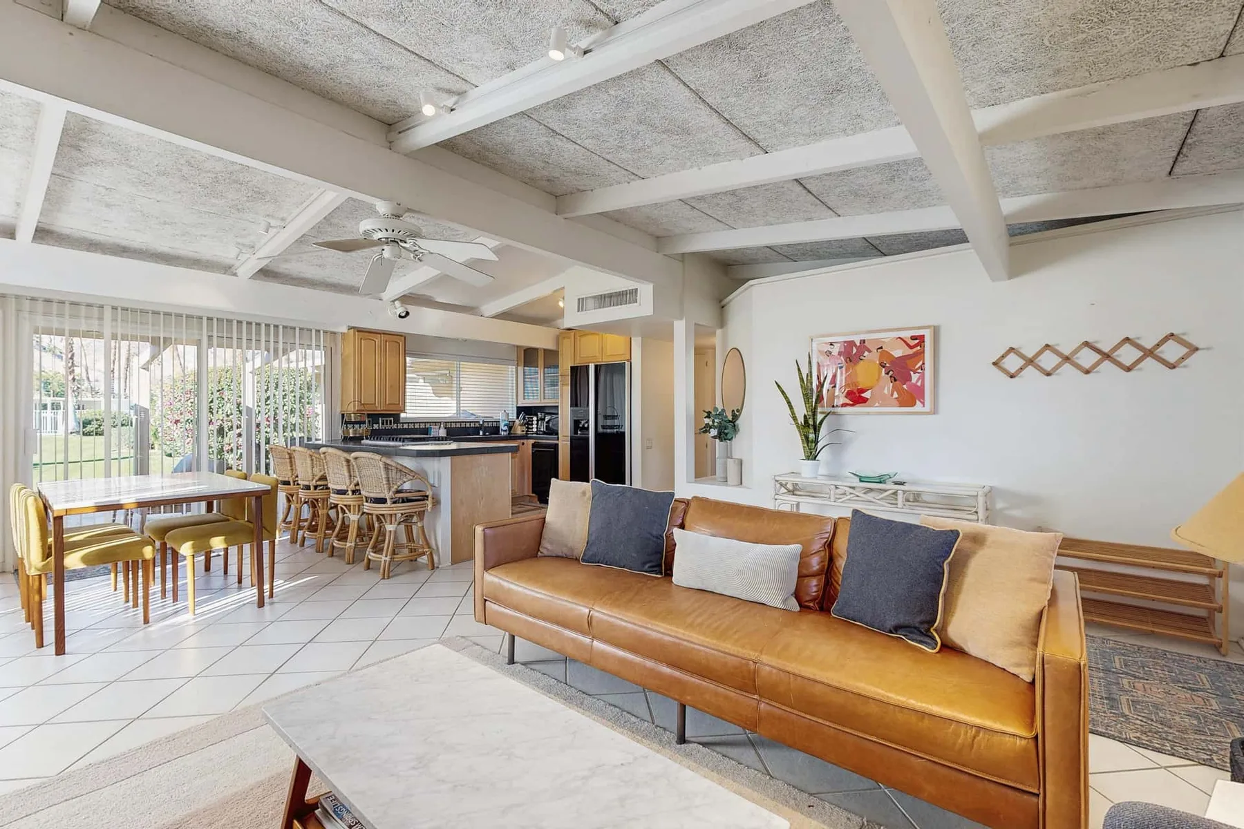 An open-plan living and dining area with a tan sofa and a kitchen.