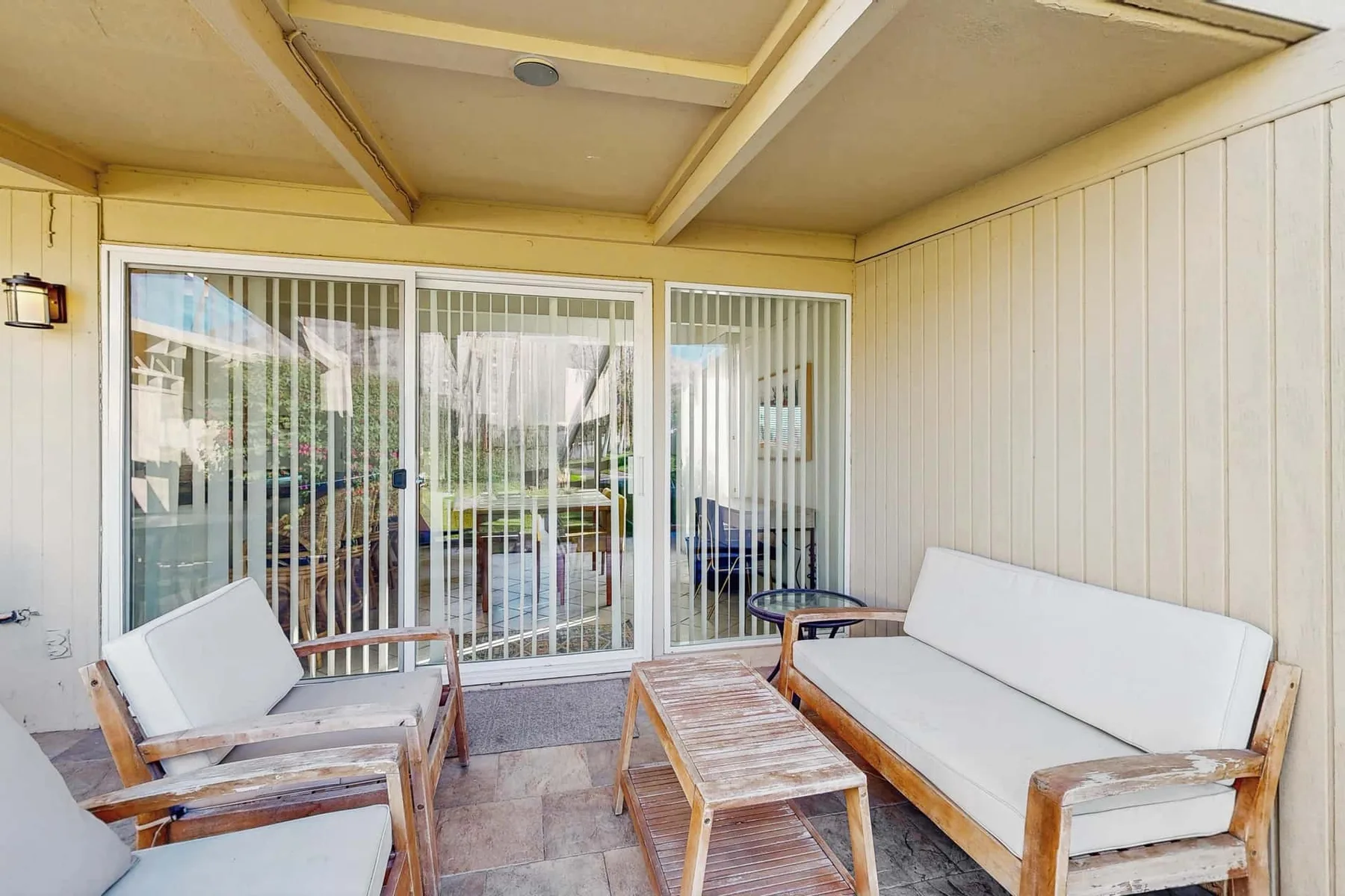 A covered patio with outdoor seating and sliding glass doors.