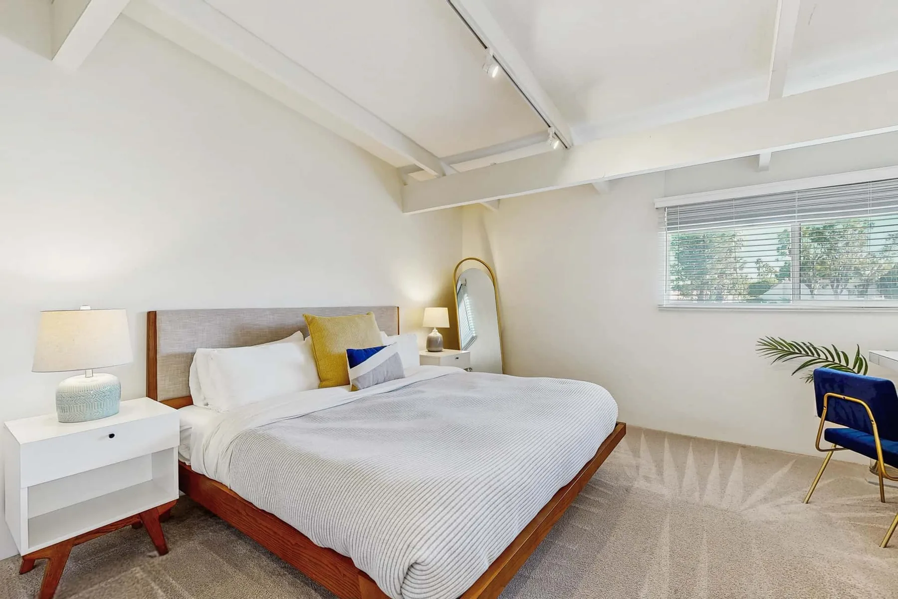 A bright bedroom with a double bed, bedside tables, and a window.