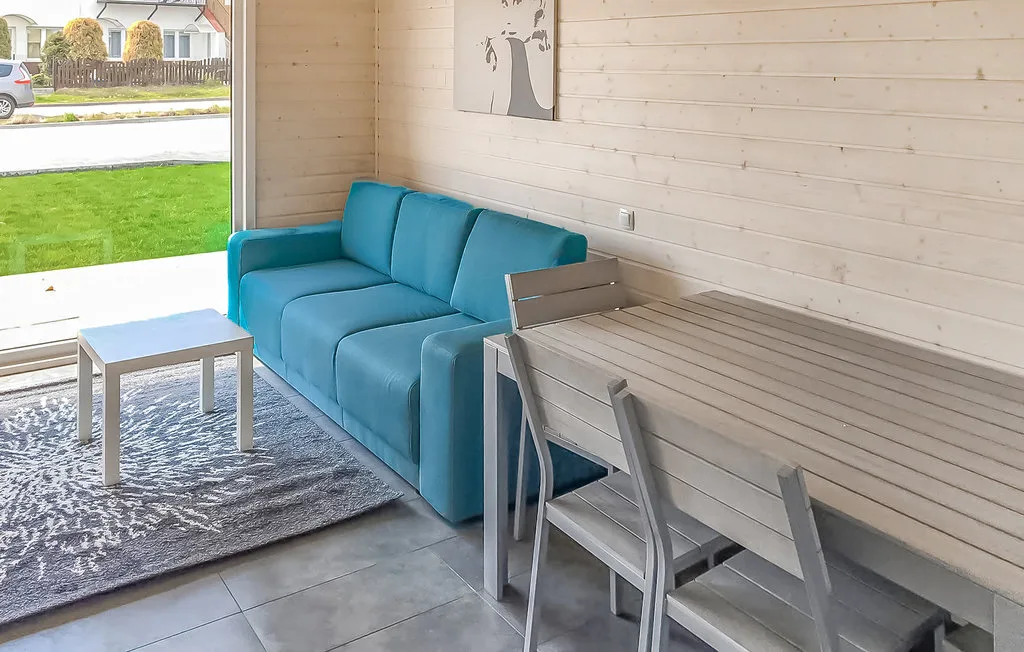 Una luminosa sala de estar y comedor con asientos azules y una mesa junto a una ventana grande.