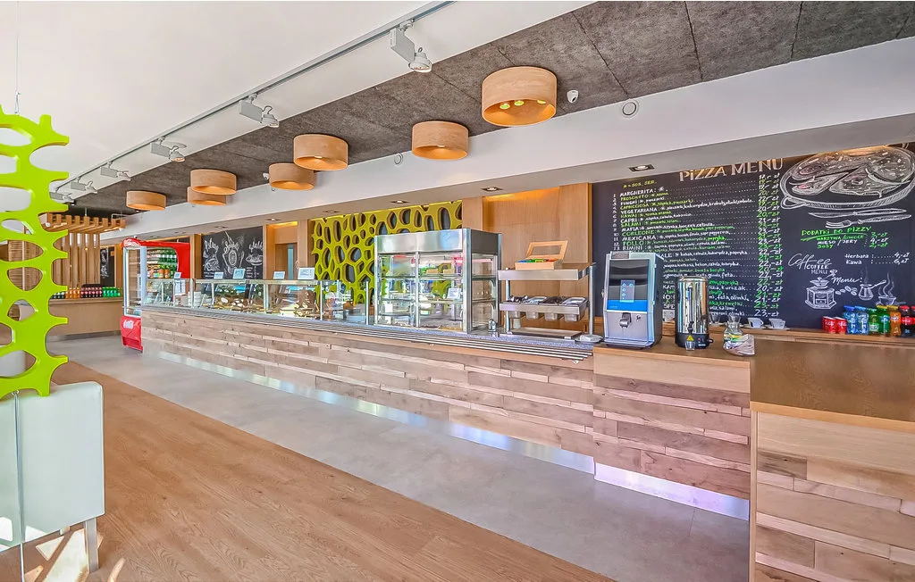Una cafetería moderna con vitrinas y un gran menú en la pared.