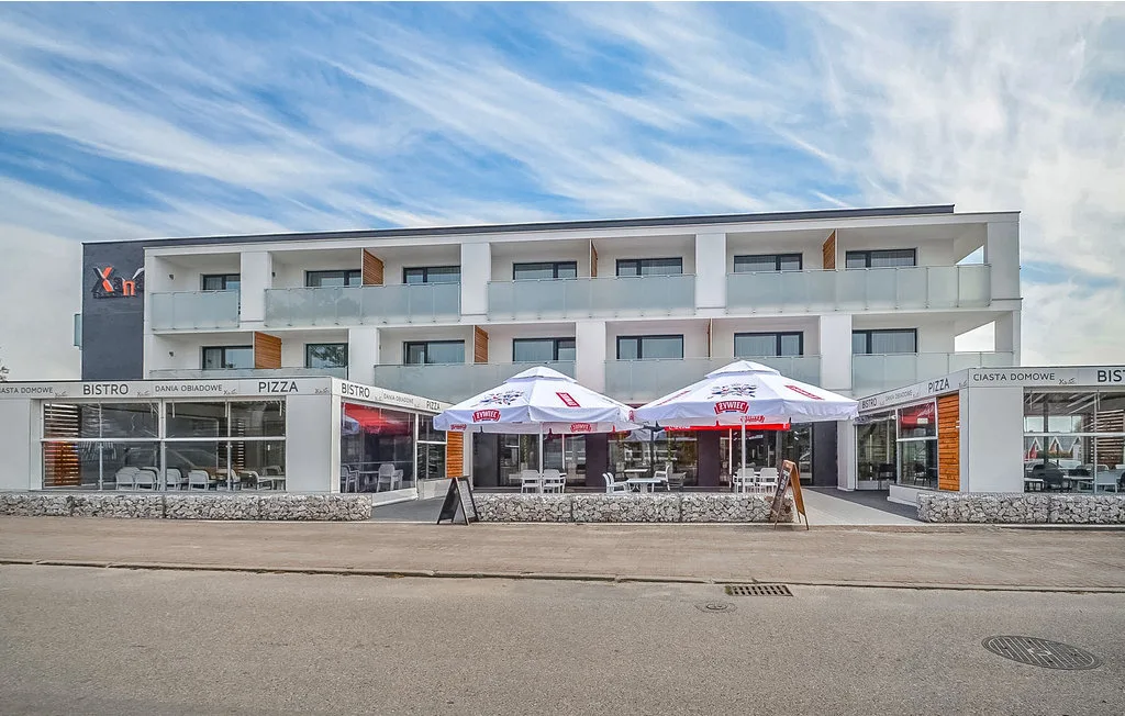 Un edificio moderno de varias plantas con restaurantes en la planta baja y mesas al aire libre.