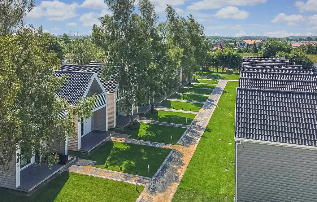Una hilera de casas pequeñas bordea un camino pavimentado en una zona residencial verde.