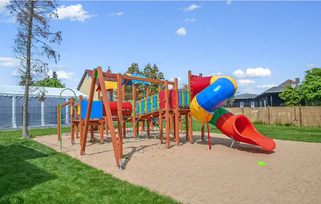 Un parque infantil colorido al aire libre, con estructuras para trepar y toboganes sobre arena.