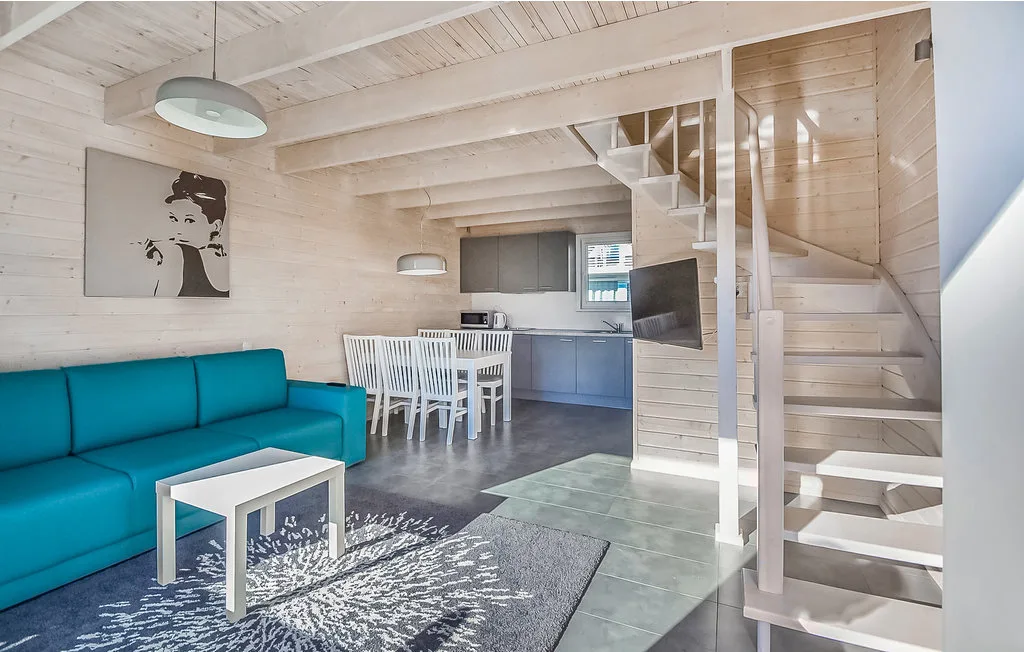 Una luminosa sala de estar y comedor con un sofá turquesa y una mesa blanca.