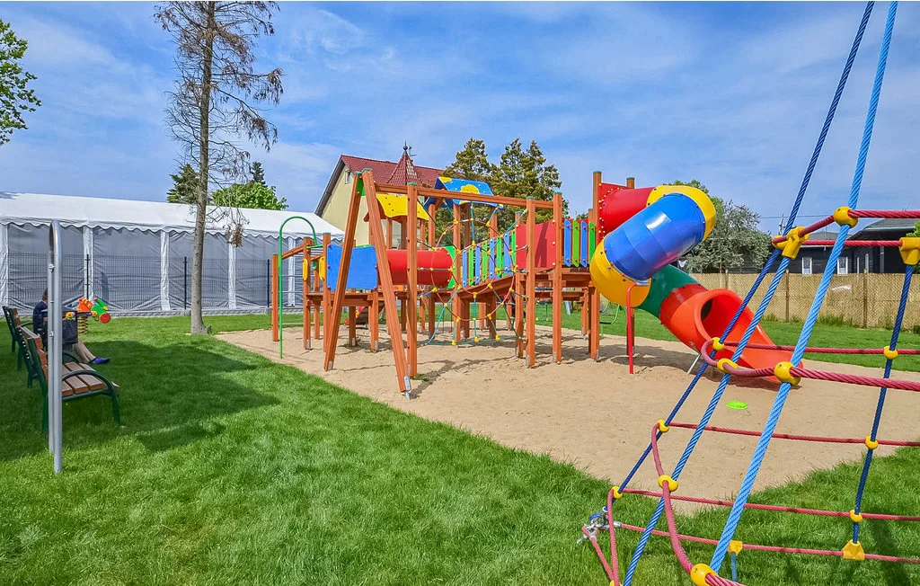 Un parque infantil al aire libre con una estructura de colores y toboganes sobre arena.