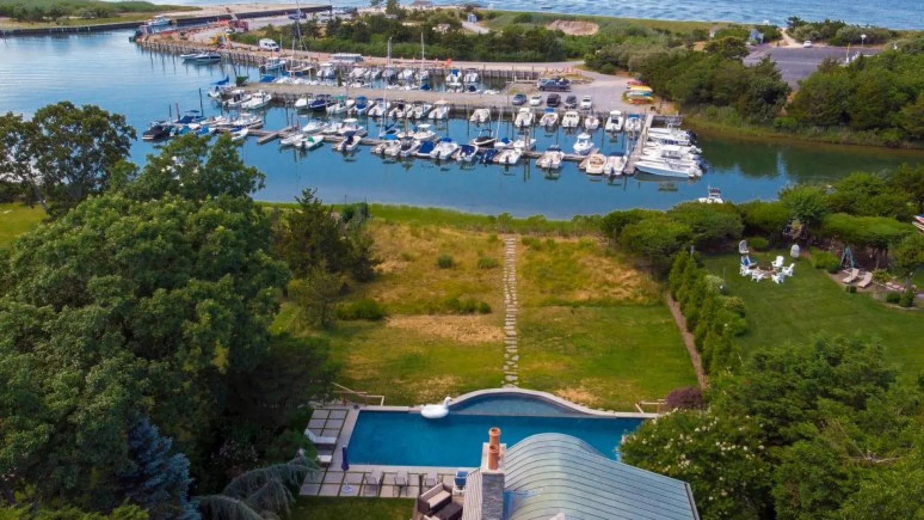 Vista aérea de una marina con embarcaciones junto a un jardín con césped.