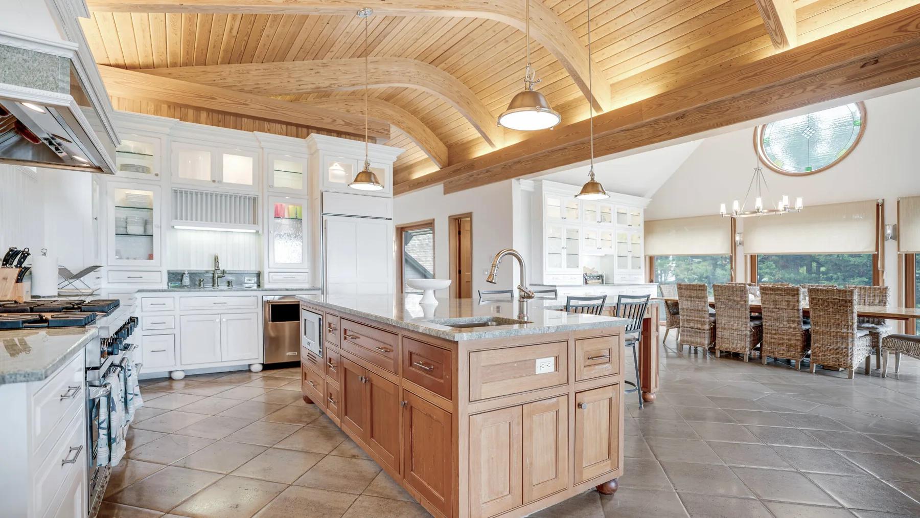 A bright kitchen with a large wooden island beneath a vaulted ceiling.