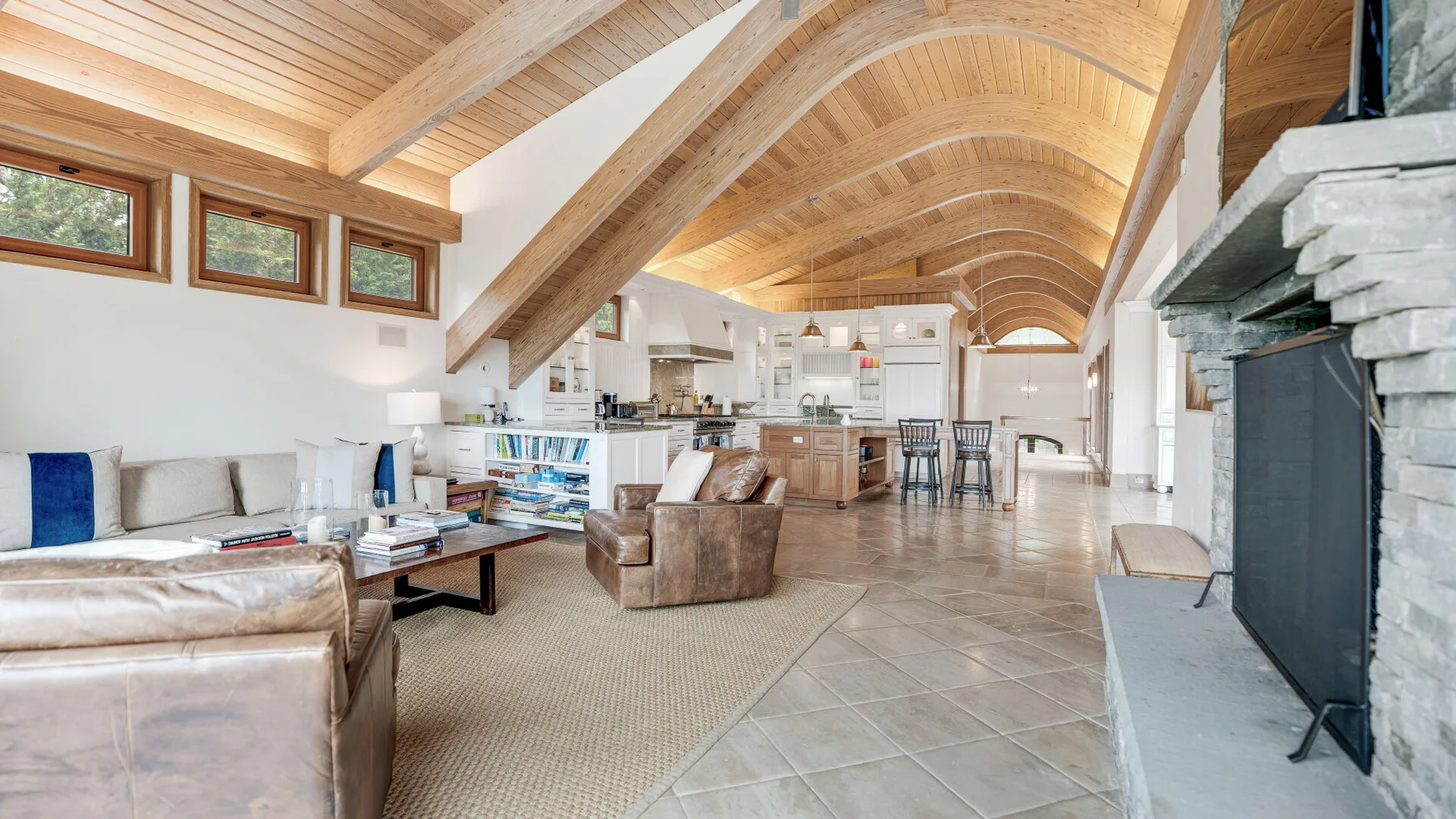 A spacious open-plan living room and kitchen with a high timber ceiling.