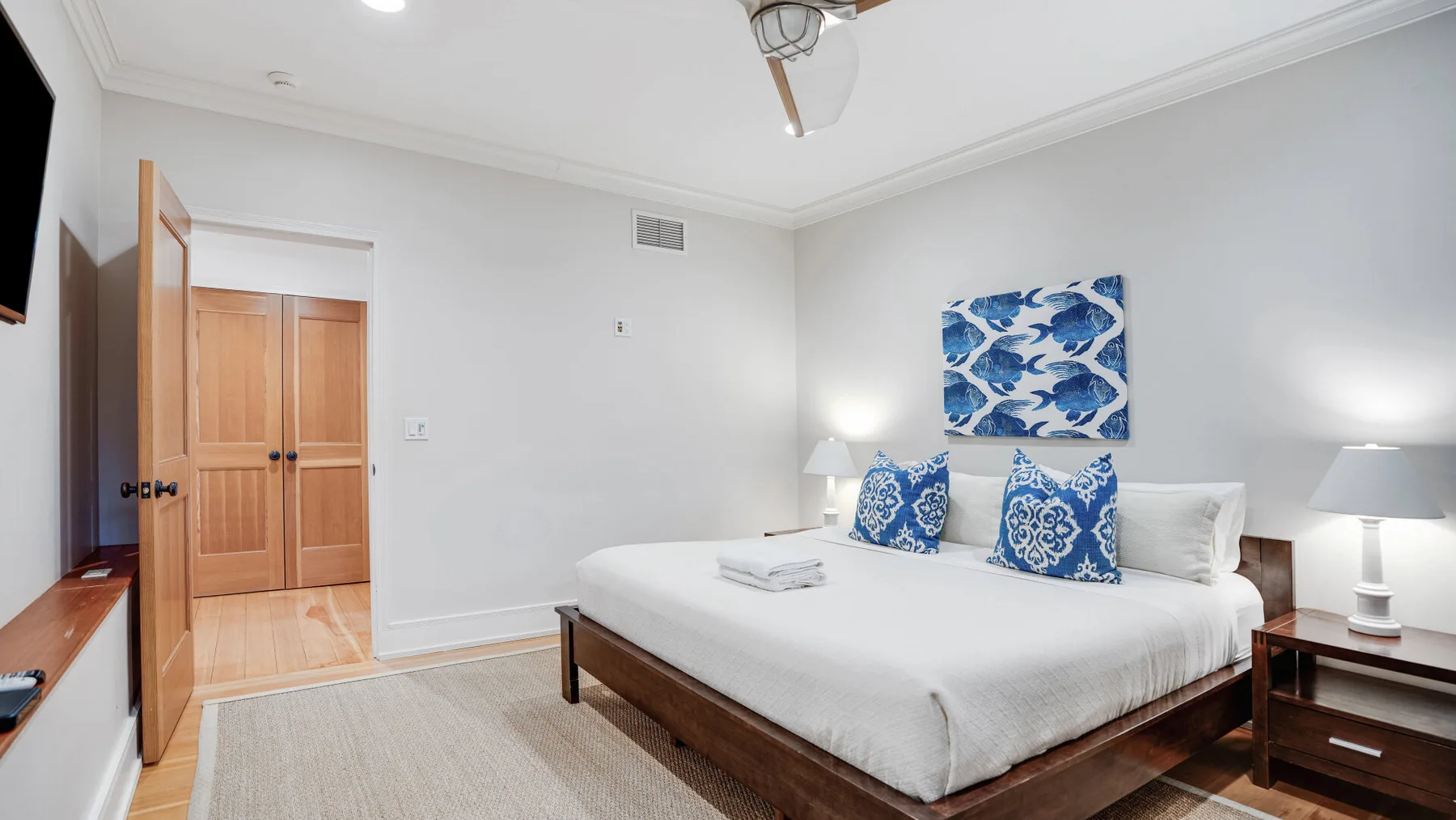A bedroom with a neatly made bed and blue patterned pillows.