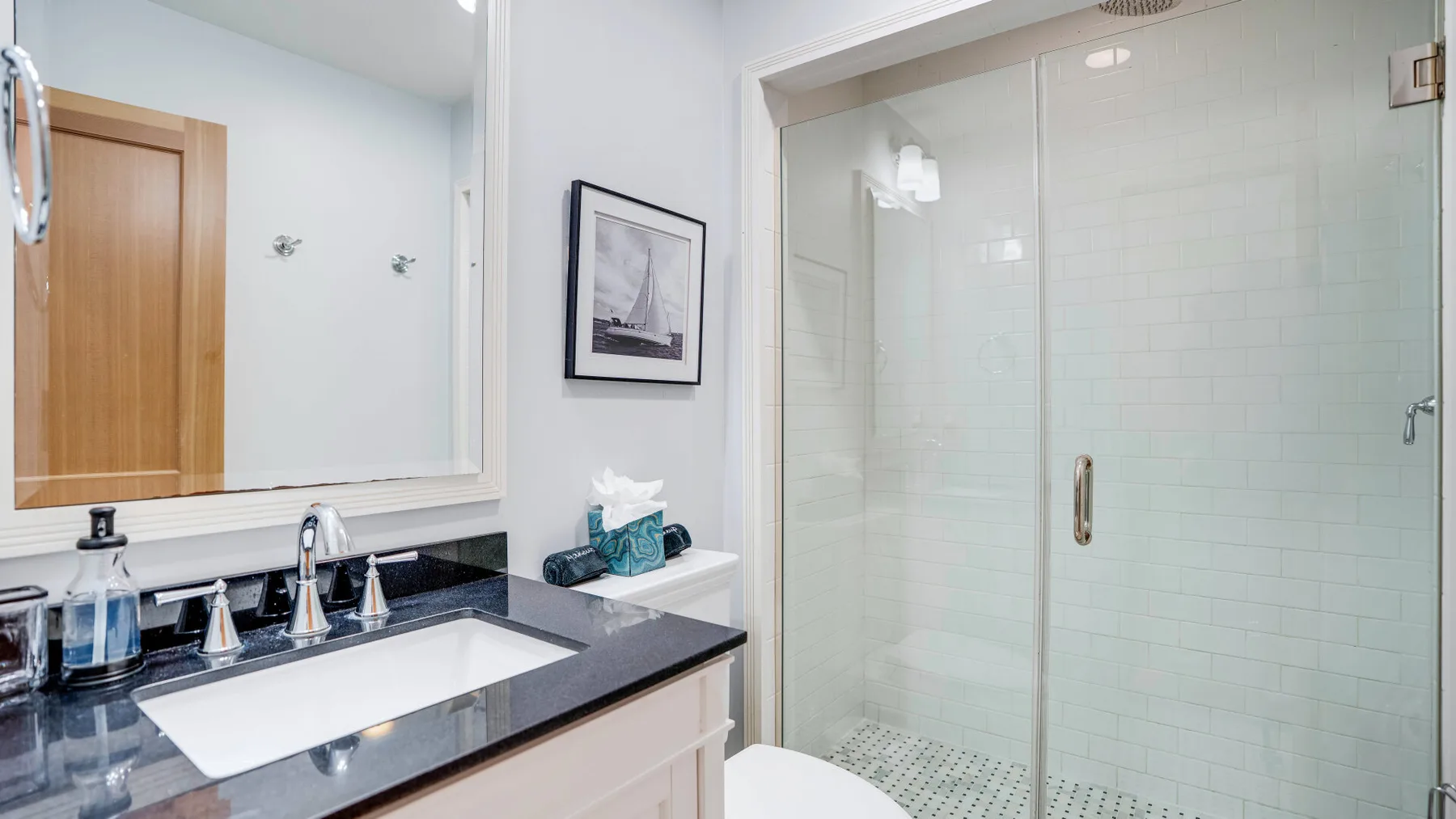 A bathroom with a long vanity beside a glass-enclosed shower.