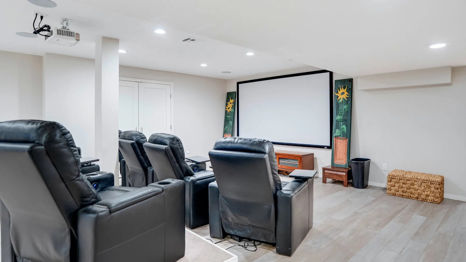 A home theater room with rows of reclining seats facing a large projection screen.