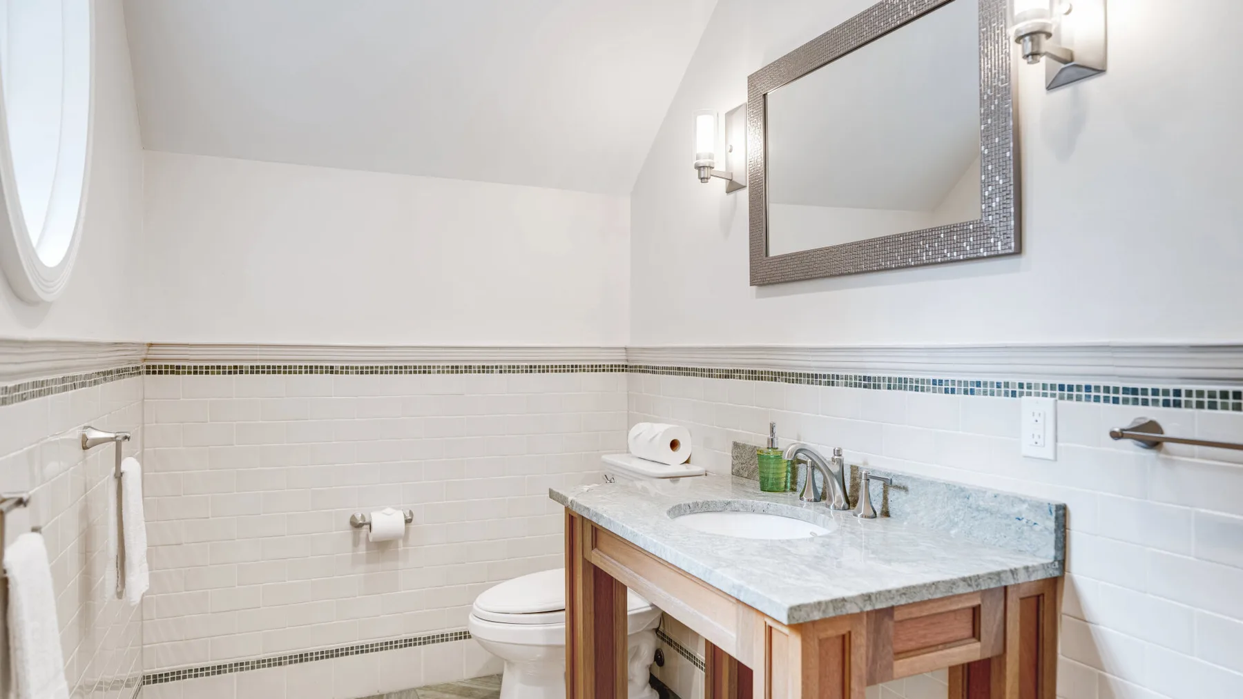 A bright bathroom with a vanity, mirror, and toilet.