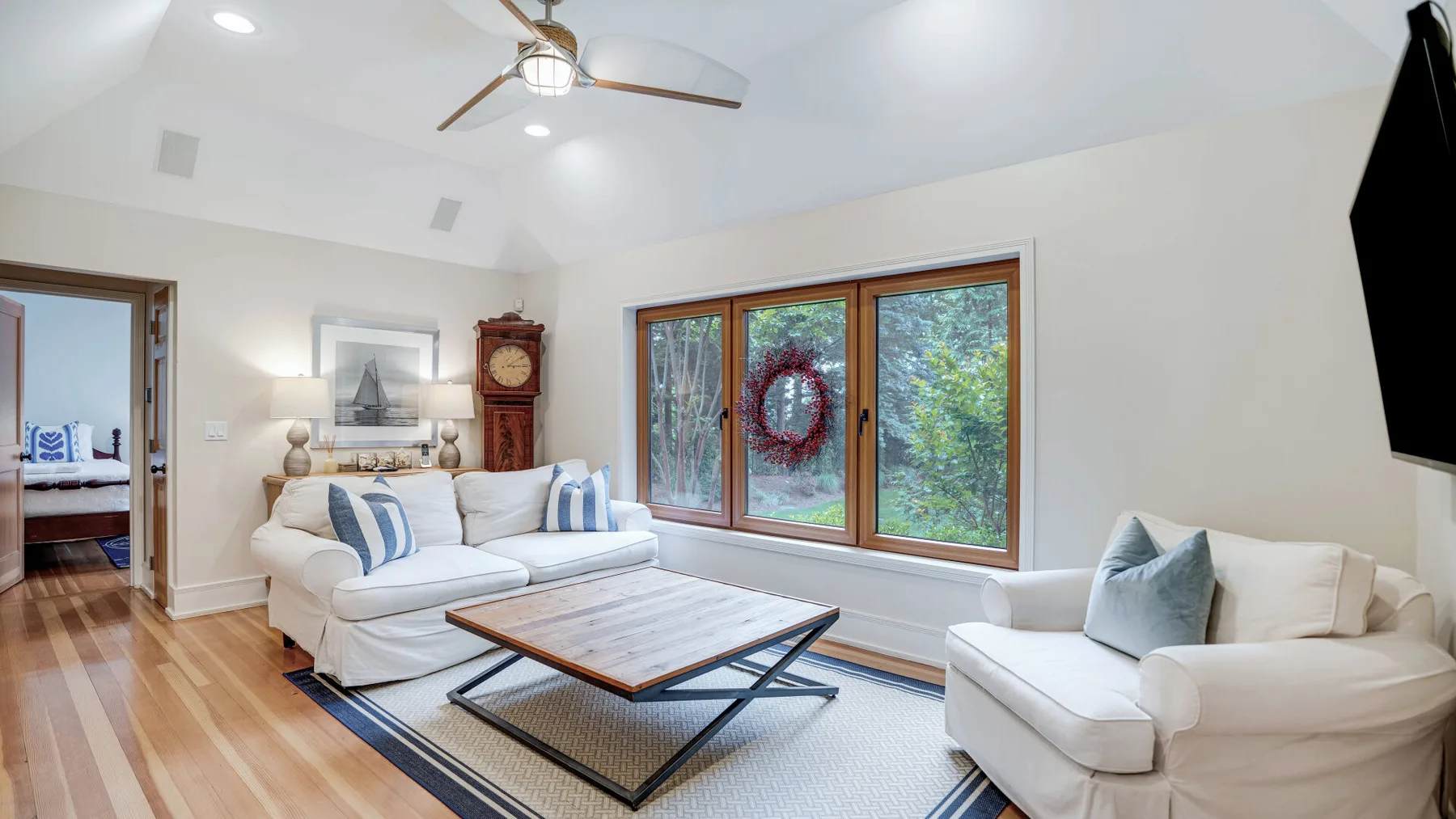 A bright living room with white seating, a coffee table, and large windows.