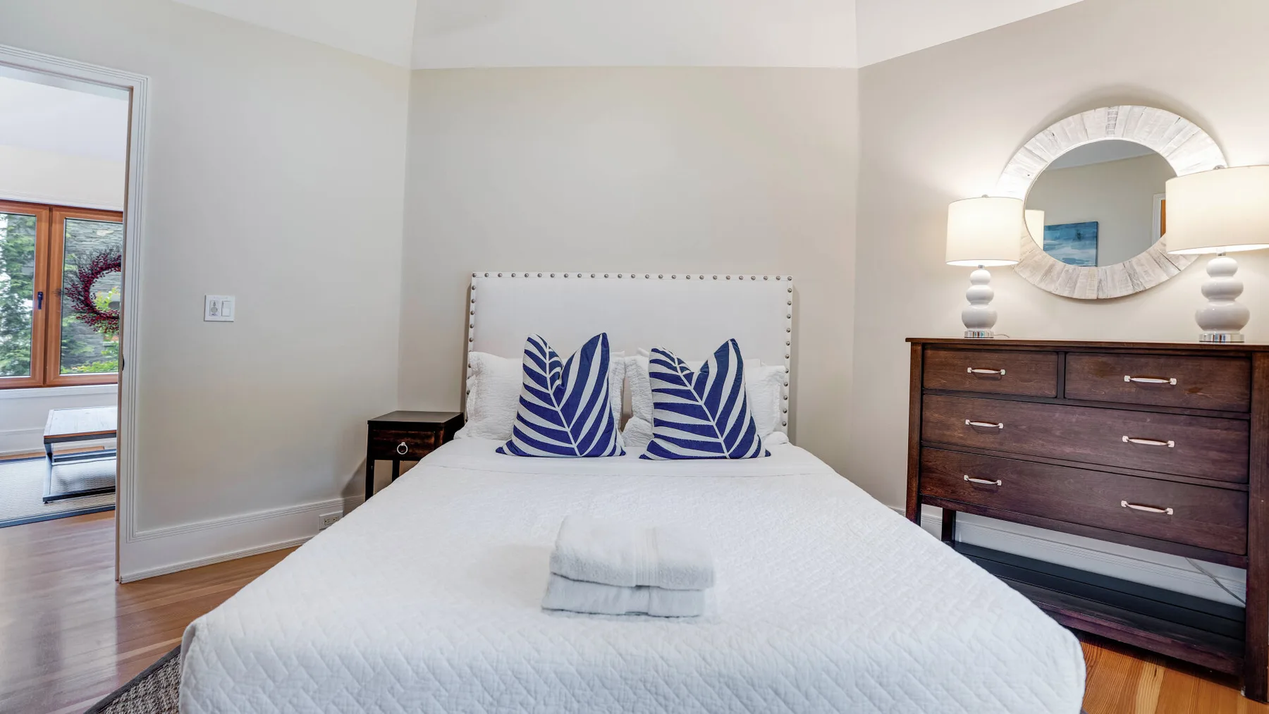 A bedroom with a neatly made bed and blue patterned pillows.