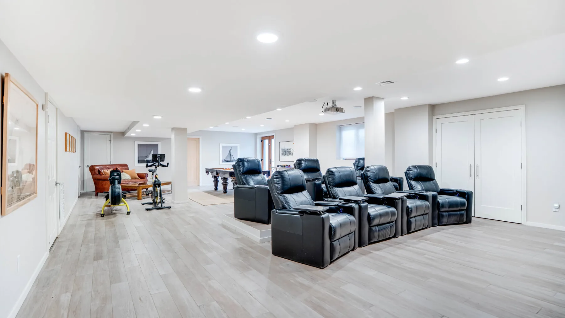 A basement media room with rows of seating facing a television.