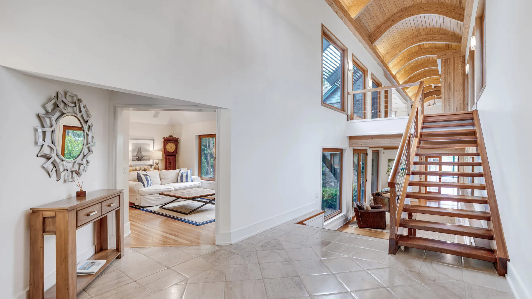 A bright interior hallway opens onto a bedroom, with a wooden staircase beside it.